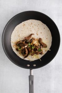 making steak quesadilla in pan.