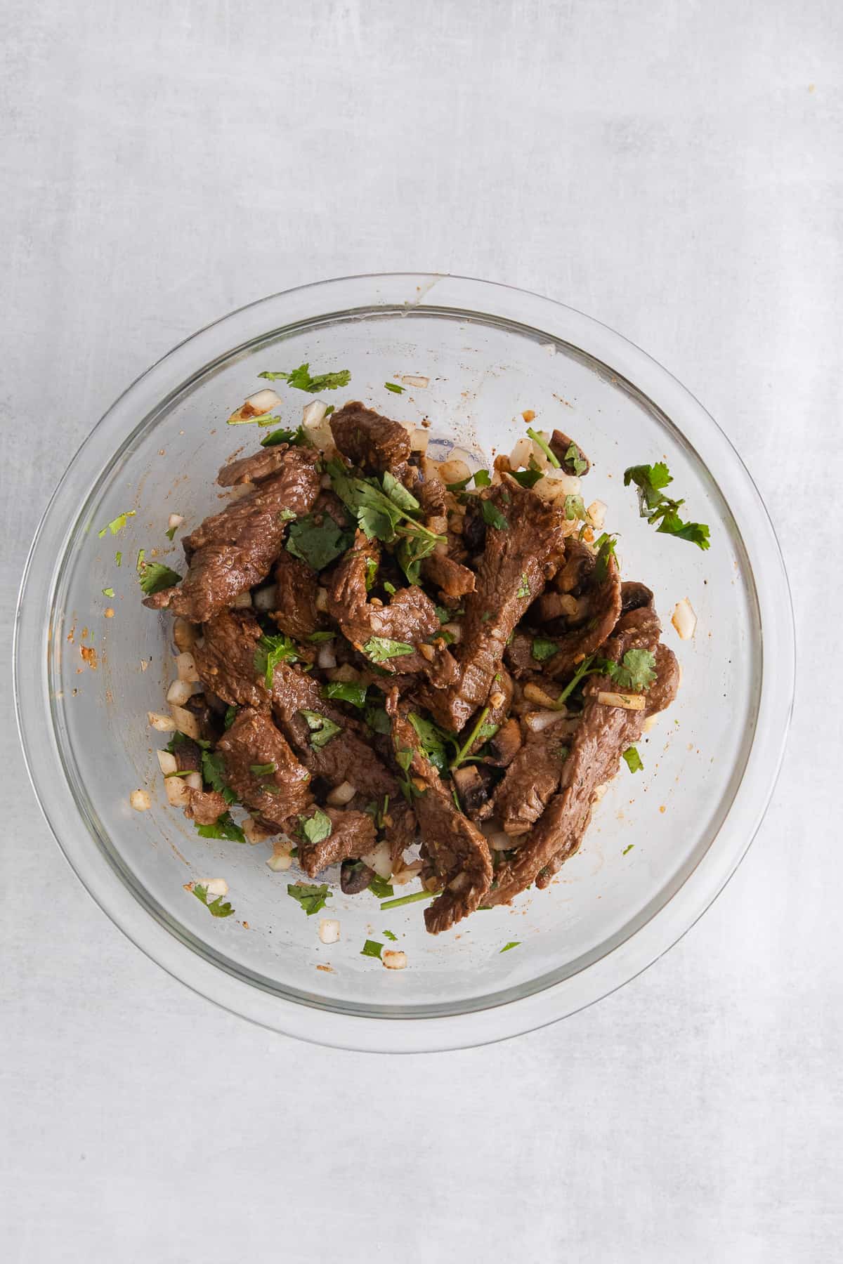 Steak, onions, and cilantro in a bowl.