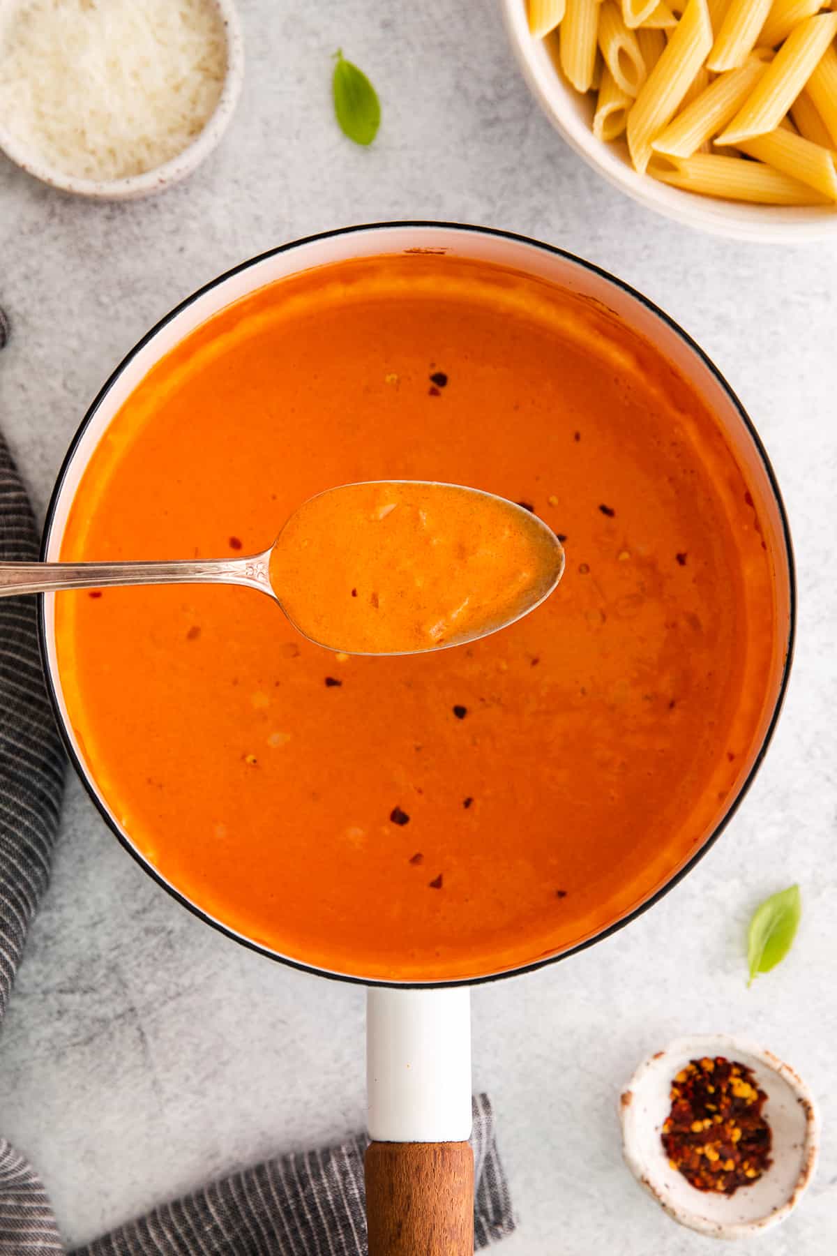 creamy vodka sauce on spoon over pot.