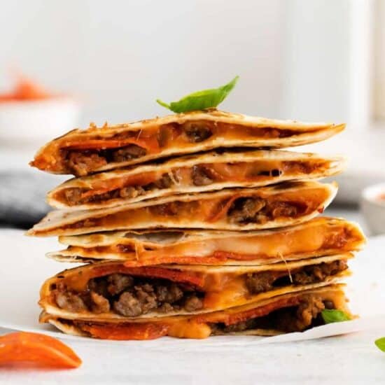 Pizza quesadilla stacked on a plate.