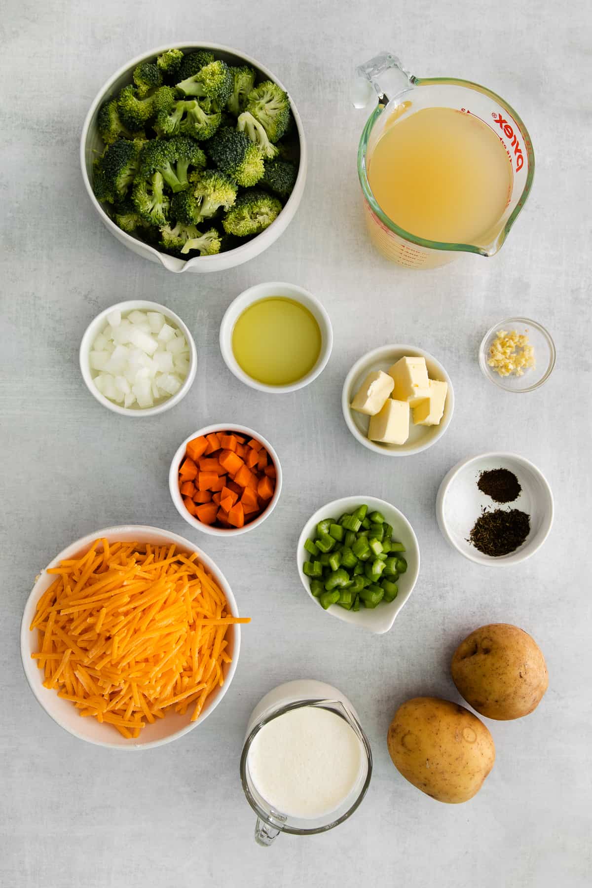 All of the ingredients for broccoli potato cheese soup in small bowls. 