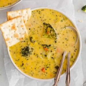 Broccoli potato soup in a bowl with crackers on the side.