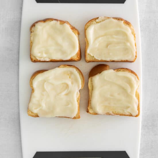 four slices of bread with cream cheese on a cutting board.