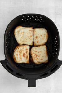 a black air fryer with slices of bread in it.