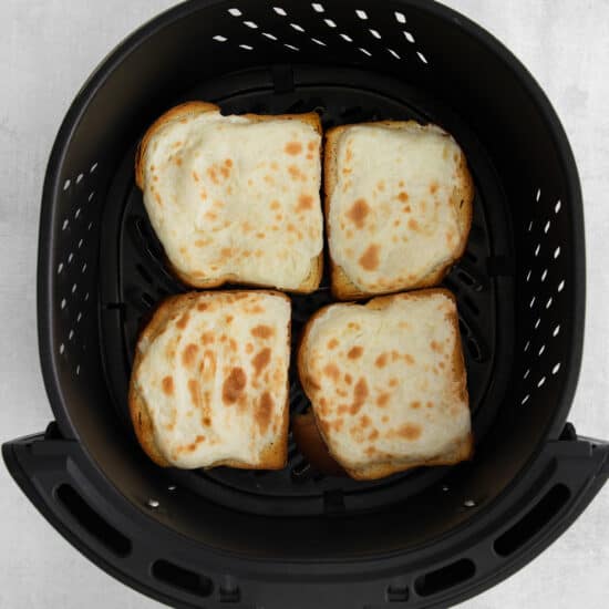 a black air fryer with slices of bread in it.