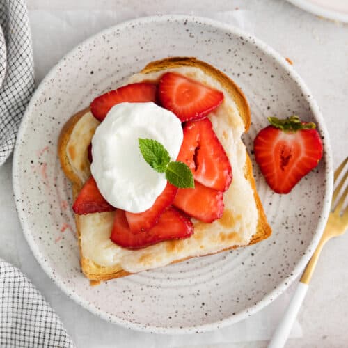 a plate of strawberry toast with whipped cream and strawberries.