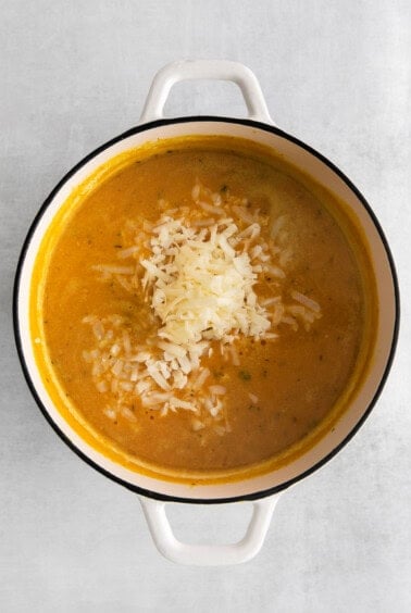 adding cheese to soup in pot.
