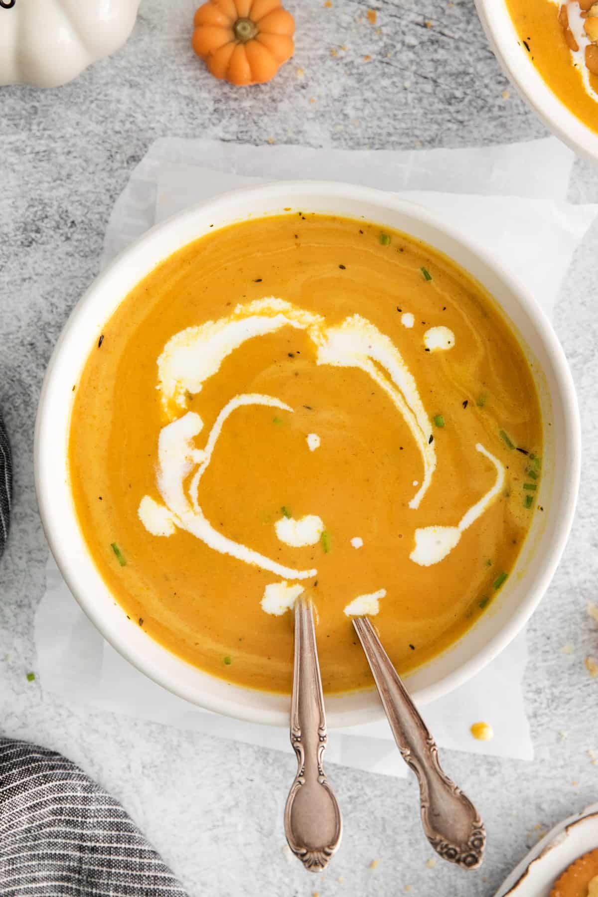 bowl of coconut pumpkin soup with 2 spoons.