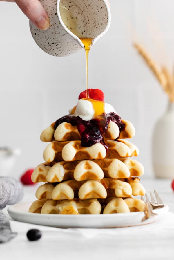 pouring maple syrup on top of waffle.