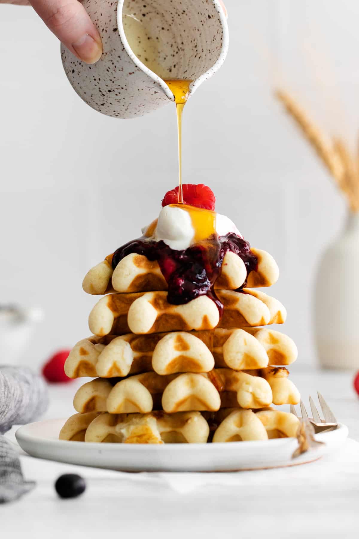 stack of waffles with berry compote and maple syrup.