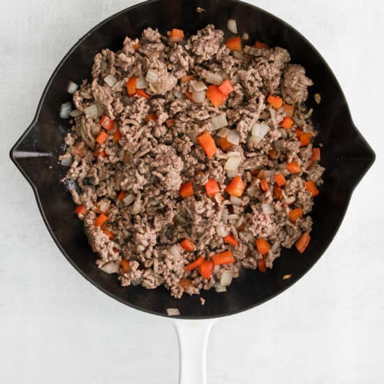 a skillet filled with ground beef and carrots.