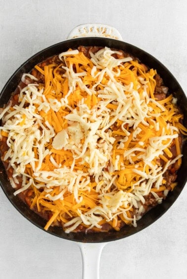 cheesy chili in a skillet on a white background.