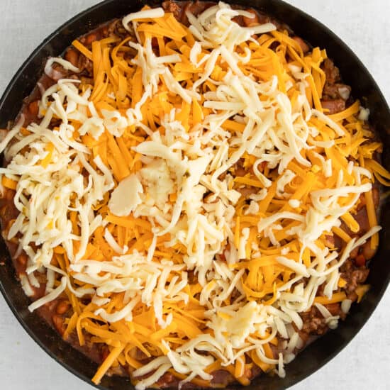 cheesy chili in a skillet on a white background.
