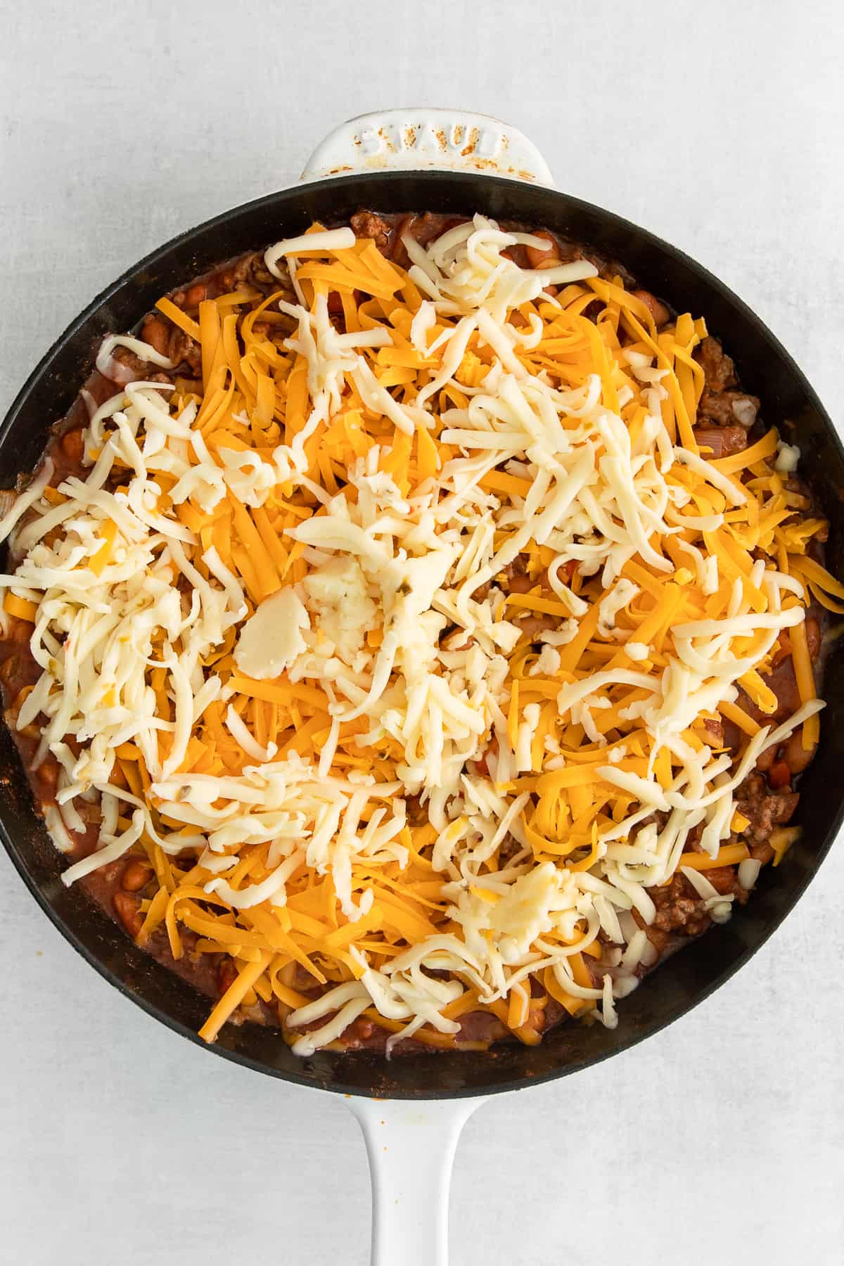 Cheesy frito taco skillet topped with shredded cheese.