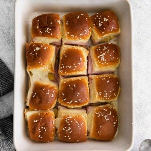 ham and cheese sliders in a white baking dish.