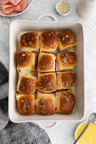 ham and cheese sliders in a white baking dish.