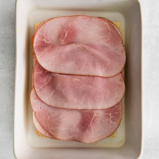 sliced ham in a square dish on a white background.