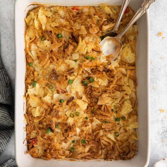 a hot casserole dish filled with mashed potatoes, onions, and chicken salad.