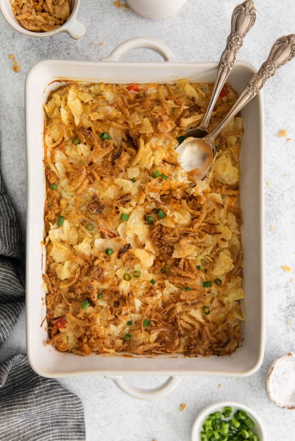 a hot casserole dish filled with mashed potatoes, onions, and chicken salad.