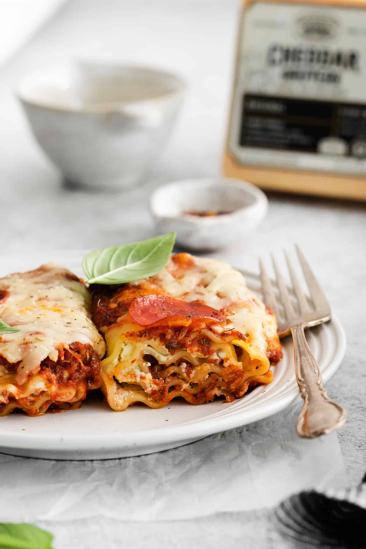 Pizza lasagna roll up on a plate with a fork.