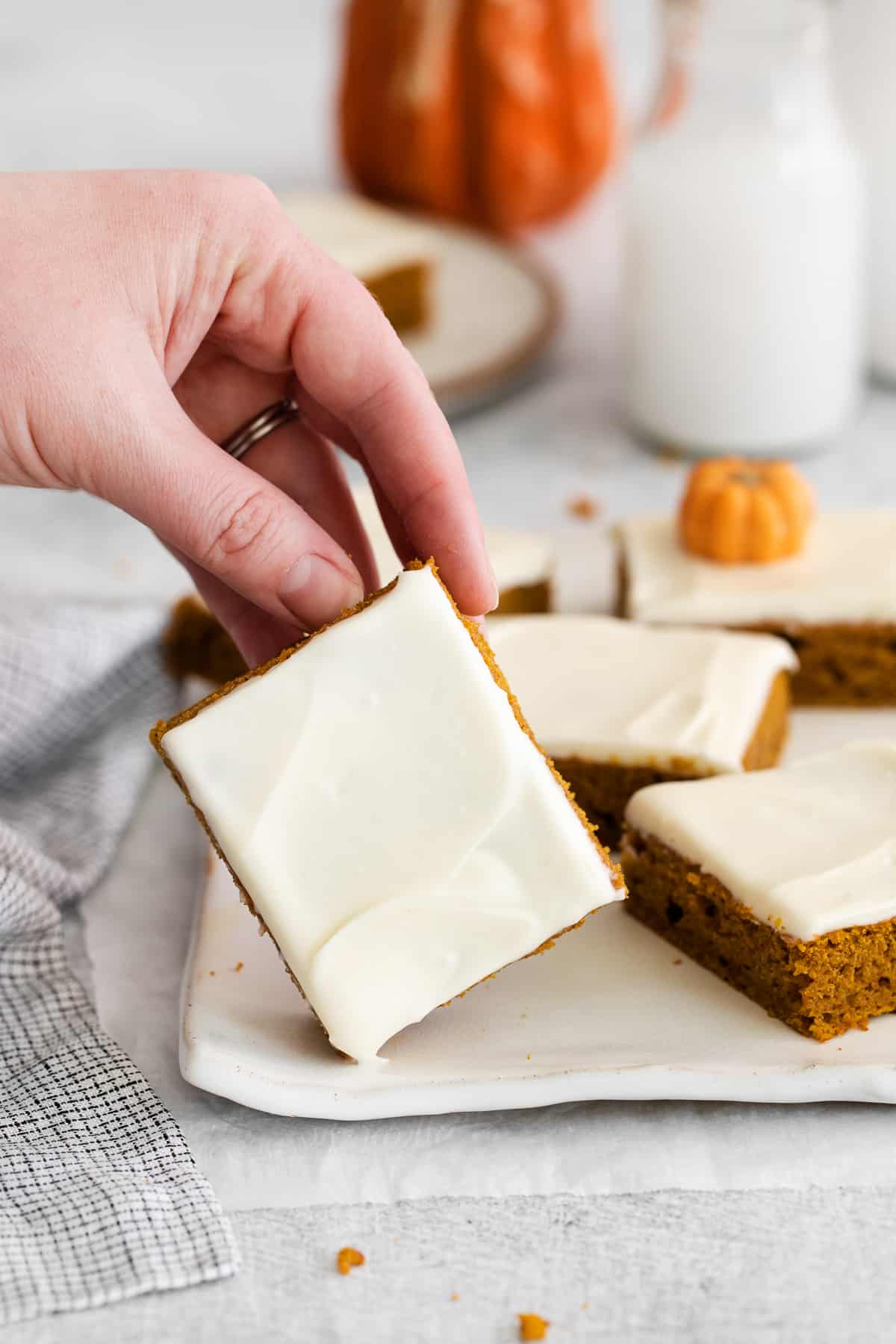 Pumpkin bar on a plate being held by a hand.