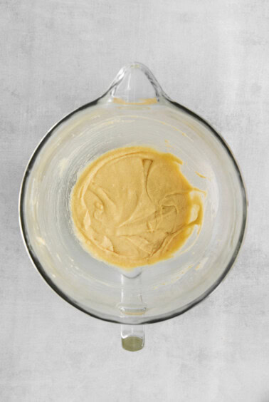 a glass bowl filled with a yellow batter.