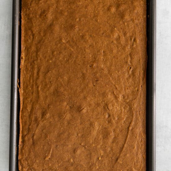 a square brownie in a baking pan on a white surface.