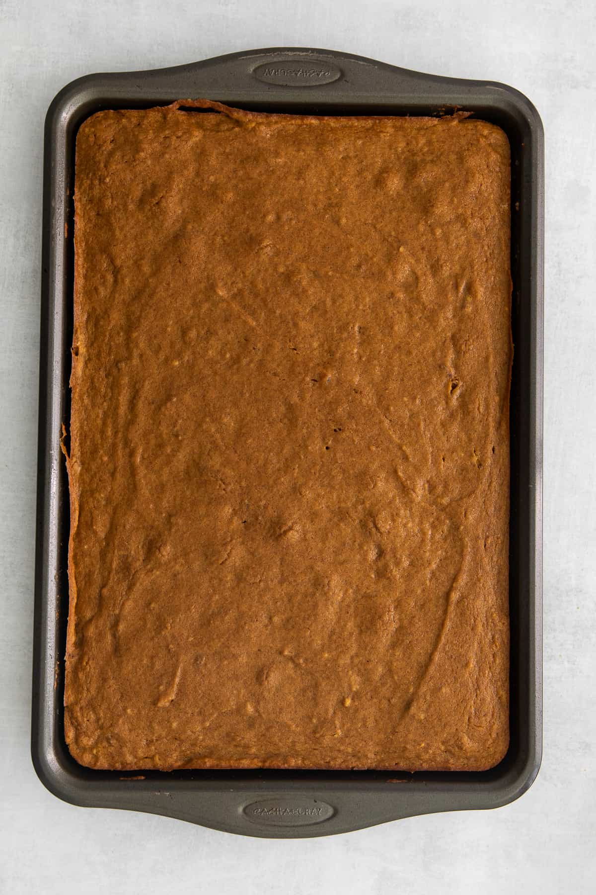 These pumpkin bars are as easy as they are delicious. Packed with simple ingredients and topped with a yummy cream cheese frosting, this dessert can’t be beat! Pumpkin bars in a jelly roll pan.