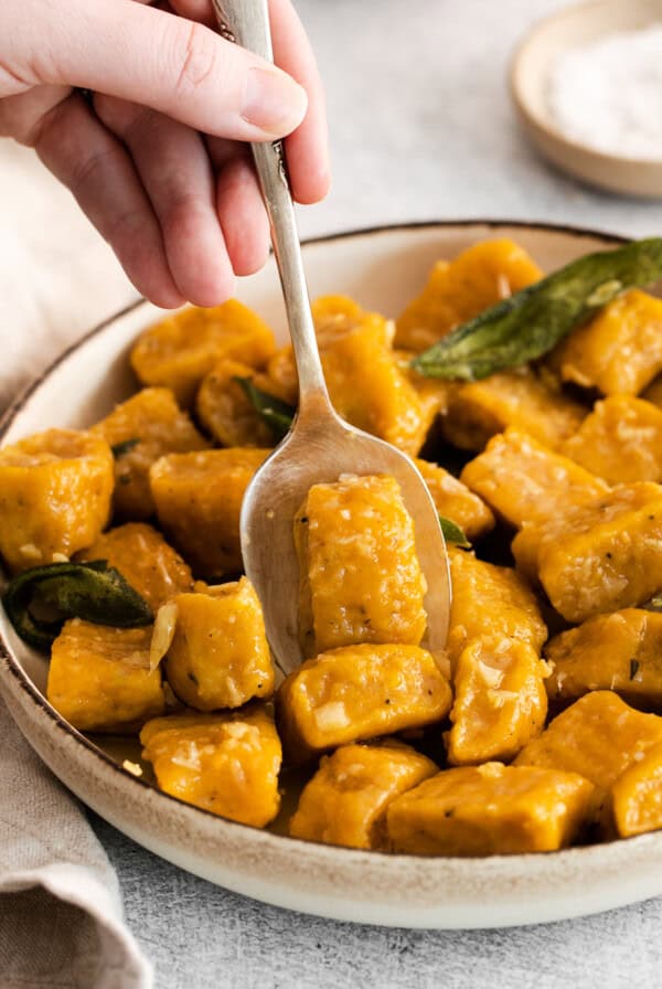 spooning ricotta gnocchi in bowl.