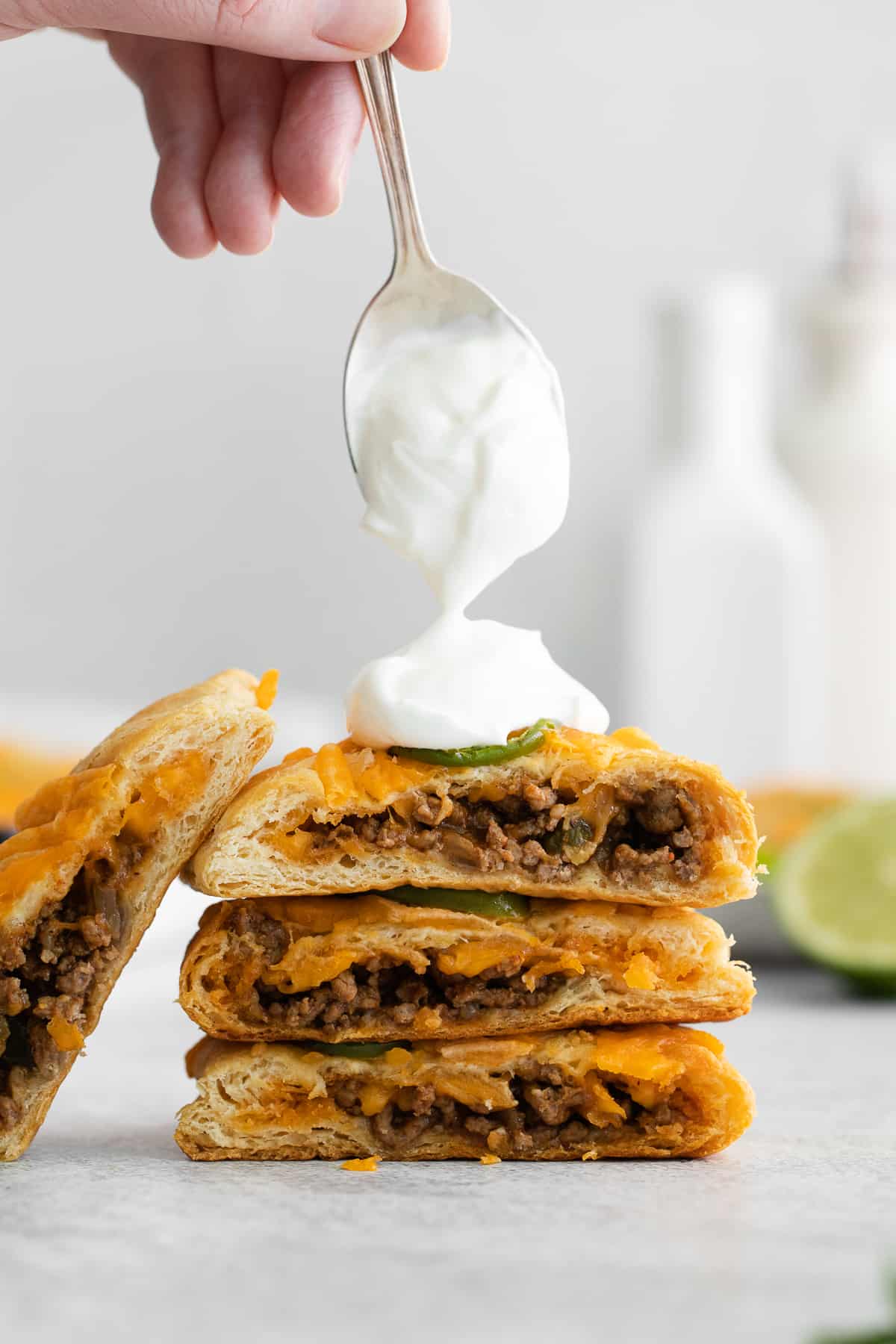 Taco pockets topped with sour cream on a spoon.