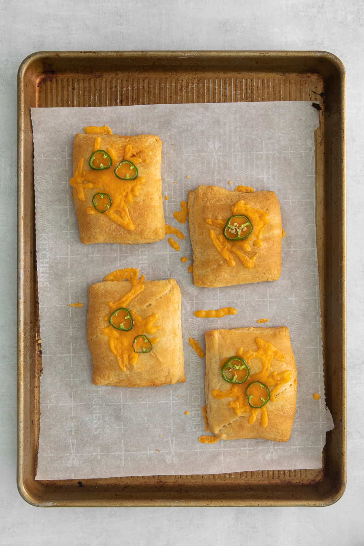 Baked taco pockets topped with sliced jalapenos.
