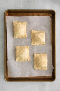 four pastry squares on a baking sheet.