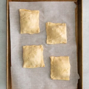 four pastry squares on a baking sheet.