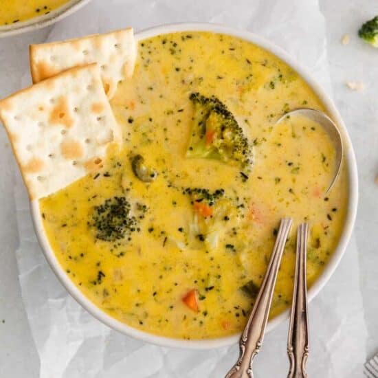 Broccoli potato cheese soup with crackers on the side.