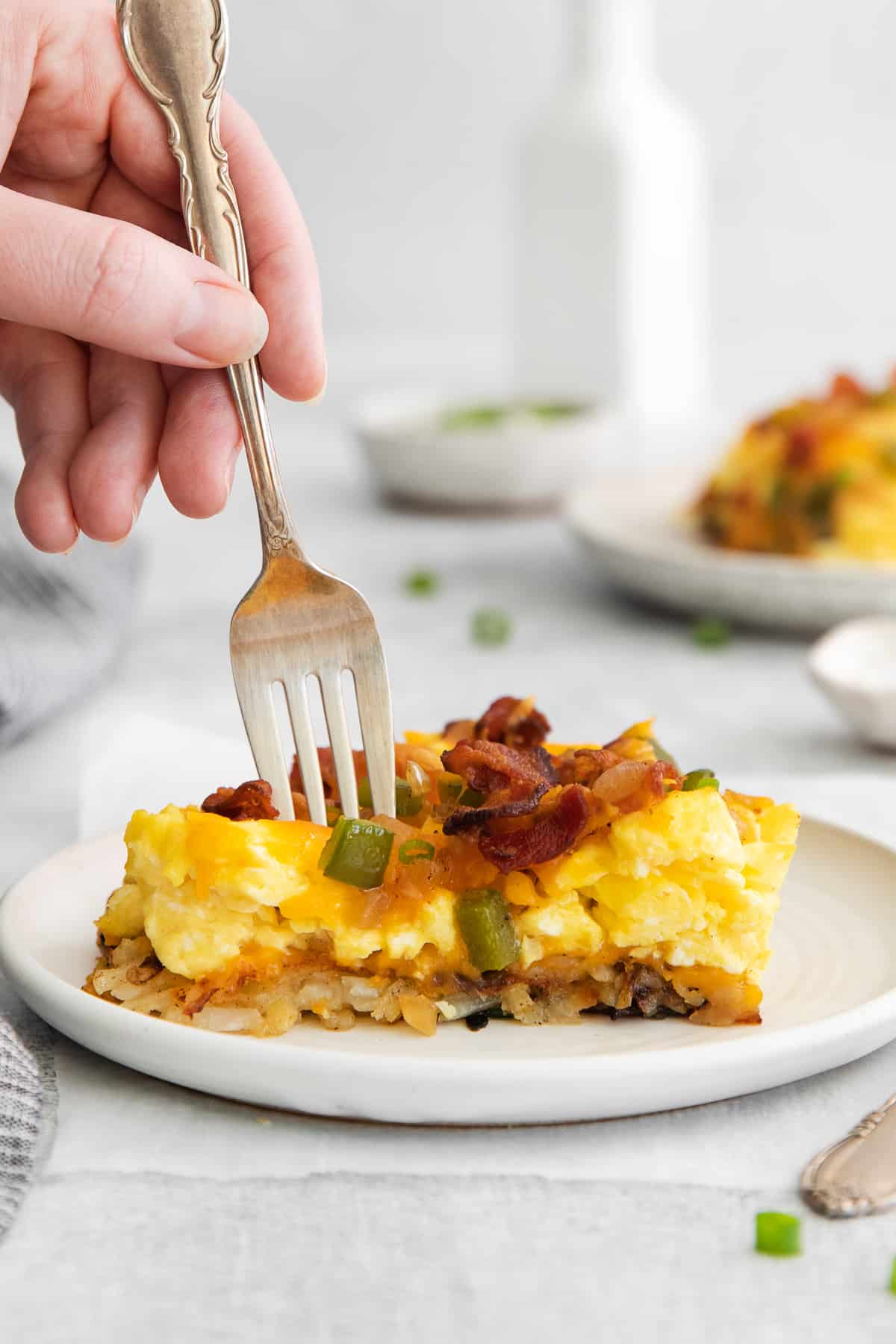 Slice of breakfast pizza on a plate with a fork.