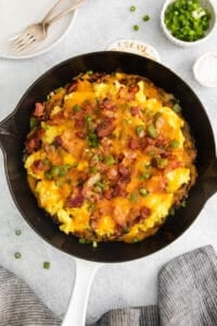 a skillet filled with eggs, bacon and cheese.