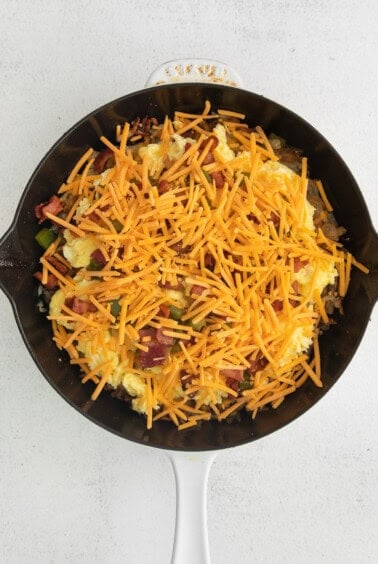 a skillet filled with eggs, cheese and bacon.