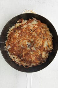 a cast iron skillet filled with fried hashbrowns.