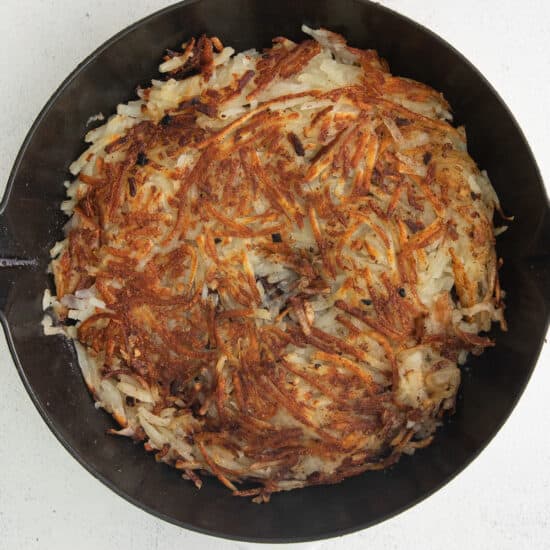 a cast iron skillet filled with fried hashbrowns.
