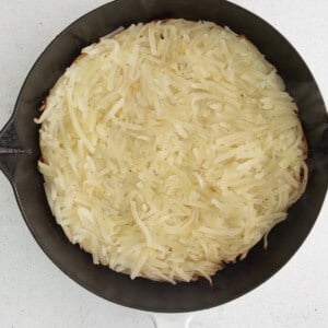 a skillet full of shredded potatoes on a white background.