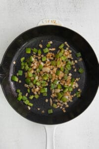 a frying pan with onions and green peppers.