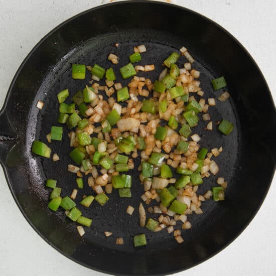 a frying pan with onions and green peppers.