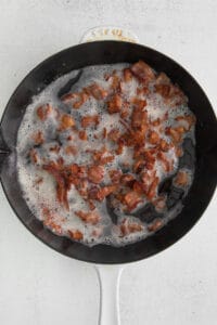 bacon in a frying pan on a white surface.