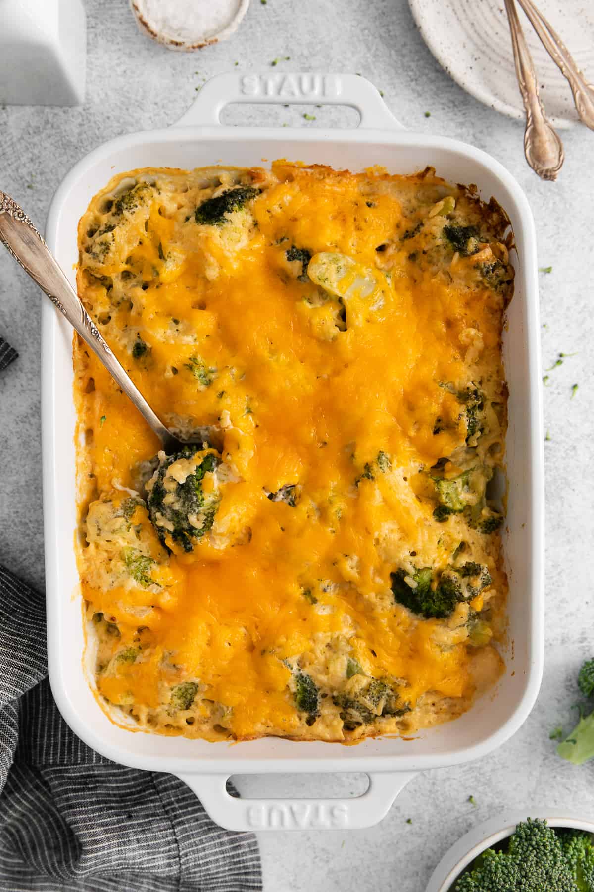 Broccoli cheese casserole topped with cheddar cheese in a casserole dish.