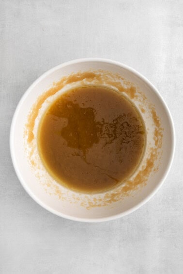 a white bowl with a brown sauce on it.