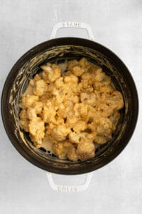 cauliflower in a slow cooker on a white surface.