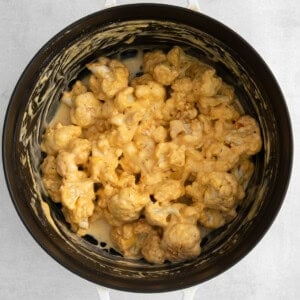 cauliflower in a slow cooker on a white surface.