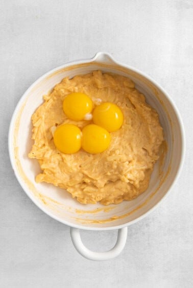 three eggs in a white bowl on a white background.
