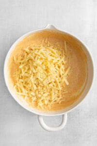shredded cheese in a white bowl on a white background.