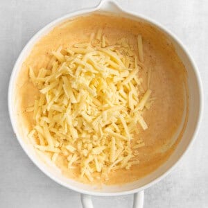 shredded cheese in a white bowl on a white background.